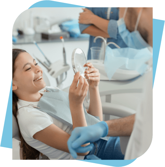 Young girl looking at her smile in a mirror at the dentist.